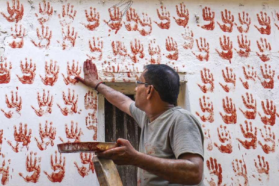 TAKE FIVE: As part of a tradition, a man leaves his handprint on a wall in Ahmedabad, Thursday, Oct. 3