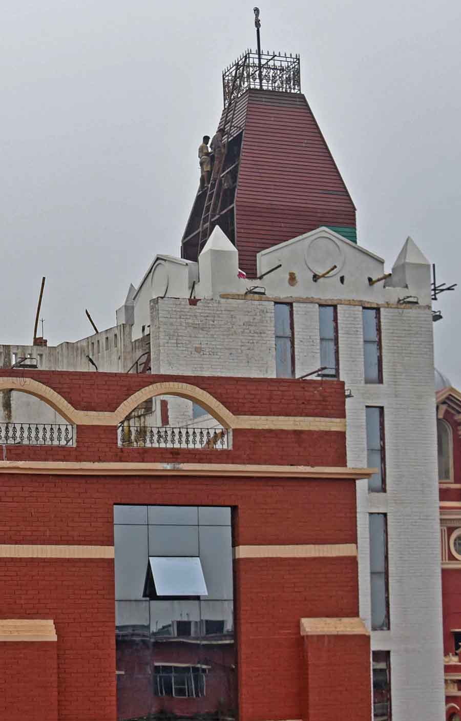 Workers engaged in maintenance work on a steeple atop the new building of the Kolkata Municipal Corporation opposite the civic headquarters near Esplanade