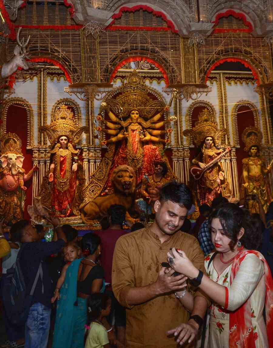 A couple check out photographs of the goddess they captured on their mobiles amid the crowd at the Singhi Park Durga Puja pandal in Gariahat on Friday evening