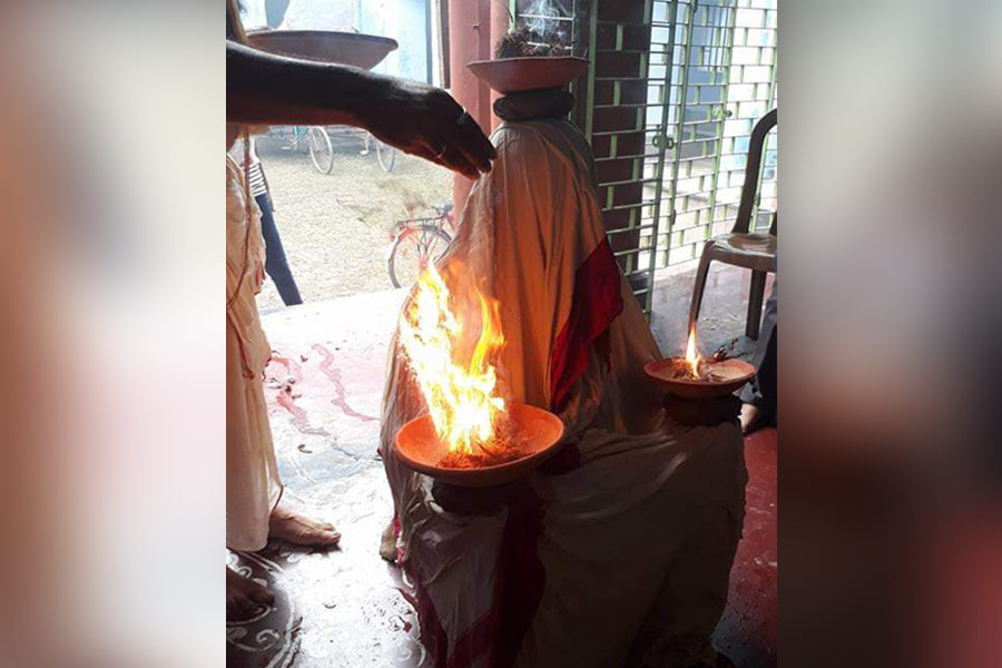 The lady of the house who performs ‘dhuno purano’ rituals sits with a long veil