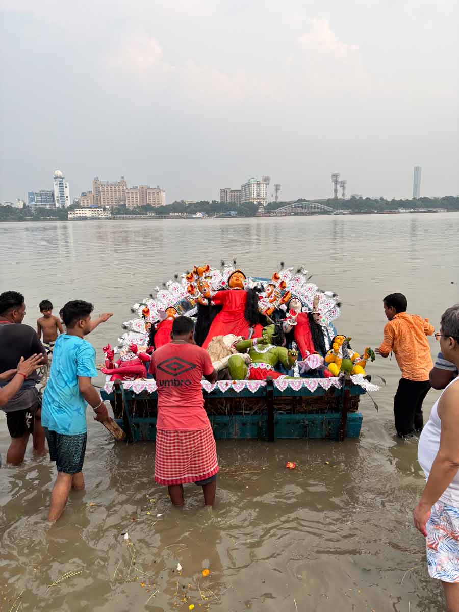 The idol is carried through the streets of Shibpur, Howrah, to Ramkrishnapur Ghat, where she is immersed in the holy Ganges. A convoy of people, on foot and in cars, follows her to the ghat, with the ‘dhaakis’ leading the way, rhythmically beating their drums. Once the idol is submerged, family members step into the water to remove the layer of paint and clay, leaving only the straw structure behind. This structure is then brought back home, with the anticipation of recreating the entire celebration all over again the following year