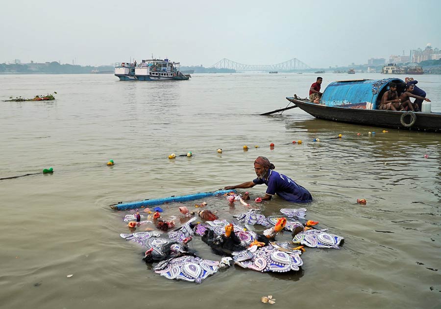 As the goddess’ long journey to Mount Kailash began, it was time for some people to take dips into the Hooghly waters to salvage for embellishments to make quick money 