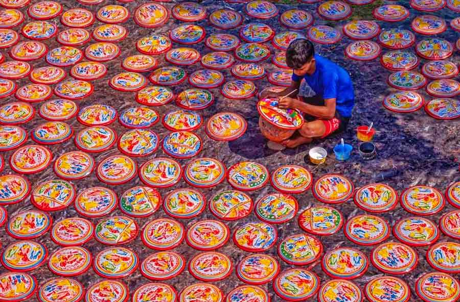 Ahead of Lakshmi Puja on October 16 and 17, an artisan puts finishing touches to a ‘Lakshmi-r pot’ (wall plate) at the Krishnanagar post office intersection on Tuesday