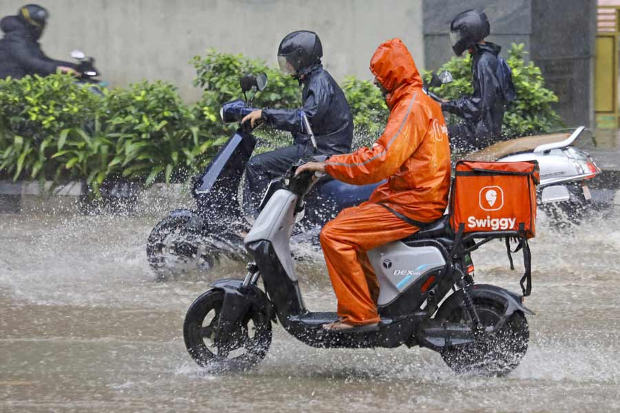 Delivery boys move through waterlogged roads amid heavy rains in Bengaluru.