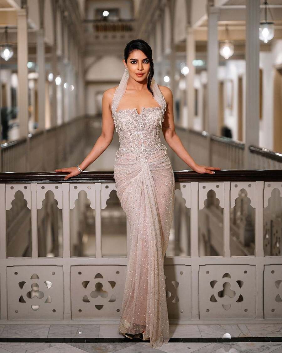 The very next day, Priyanka sparkled at the premiere of Paani in a silver sequinned body-hugging gown by Tarun Tahiliani. Embroidered with crystals and sequins, the sheer gown featured a corset bodice, sari-like folds near the waist and a draped silhouette that extended to her bun. She accessorised her look with hoop earrings and a pair of diamond bangles.