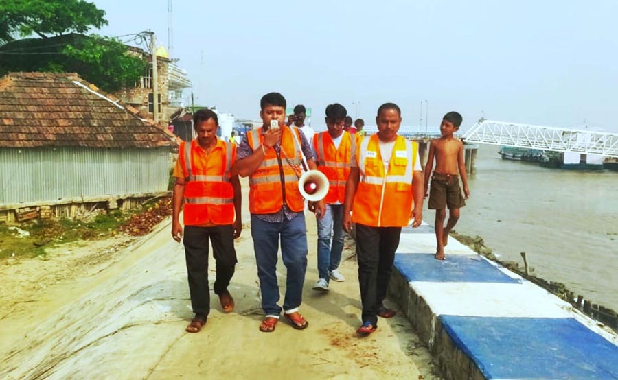 Civil defence workers warn people in the coastal areas about Cyclone Dana over public address system   at the Kachuberia Ghat near Gangasagar 