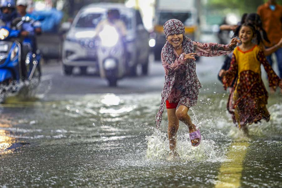 Children play on a waterlogged road after heavy rain, in Bengaluru.