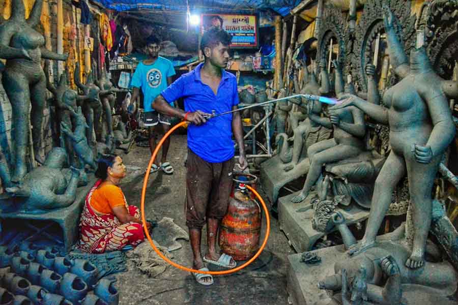 An artisan blow-dries idols of goddess Kali at a studio along the new road to Kakdwip