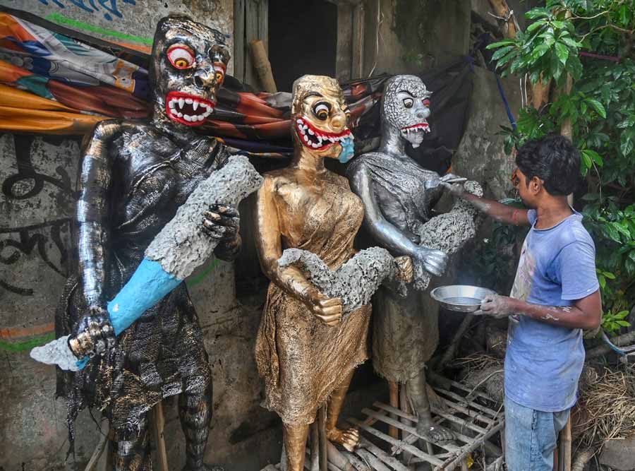 A Kumartuli artisan puts finishing touches to ghost statues to be used as props in Kali puja pandals  