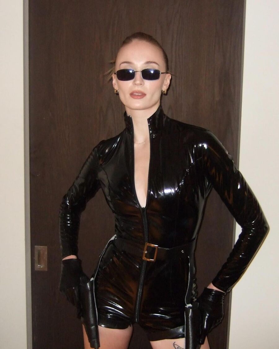 “Red or blue pill?” Sophie Turner asked, as she channelled Neo-Trinity vibes from The Matrix — paying a tribute to the 90s cult classic. She went for a futuristic, cyberpunk look in a sleek, skin-tight leather bodysuit, with her hands on fake guns in holders at her waist.