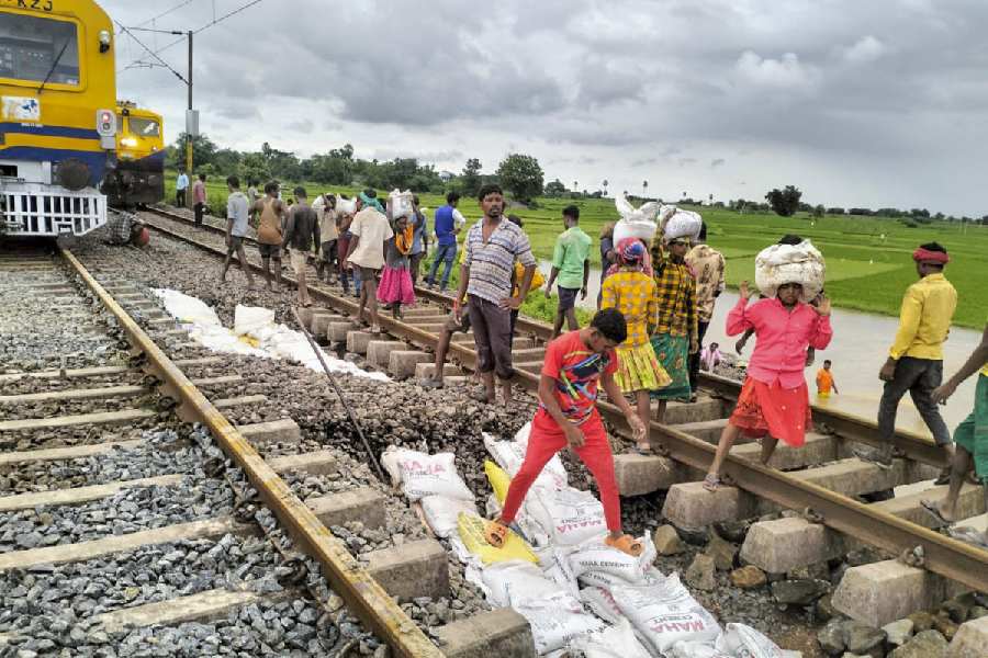 Workers restore a portion gravel under the railway track after it was washed away due to floodwaters at Kesamudram, in Mahabubabad district.