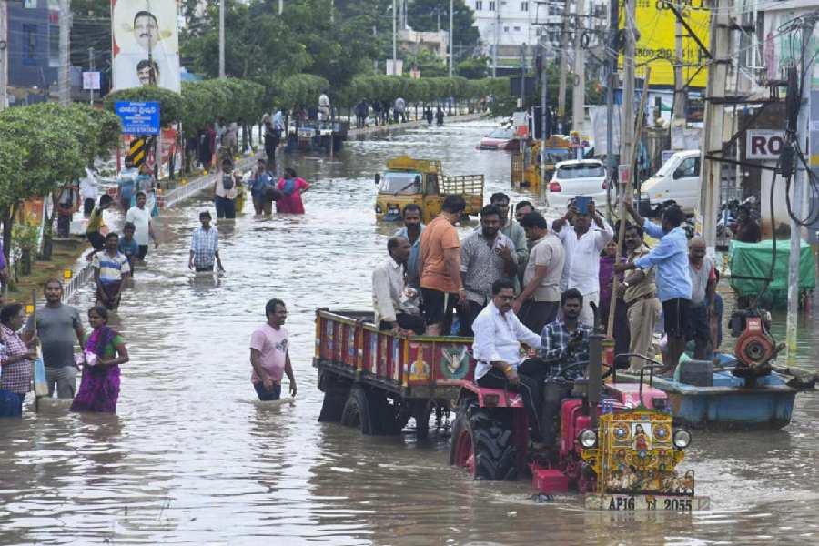 People cross a waterlogged street at the Bhavanipuram Sitara Center flood affected area, in Vijayawada, Monday, Sept. 2, 2024.