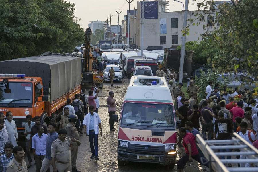 Emergency services personnel near the site where a three-storey building collapsed, crushing a truck under its debris, at Transport Nagar area in Lucknow, Saturday, Sept. 7, 2024. 
