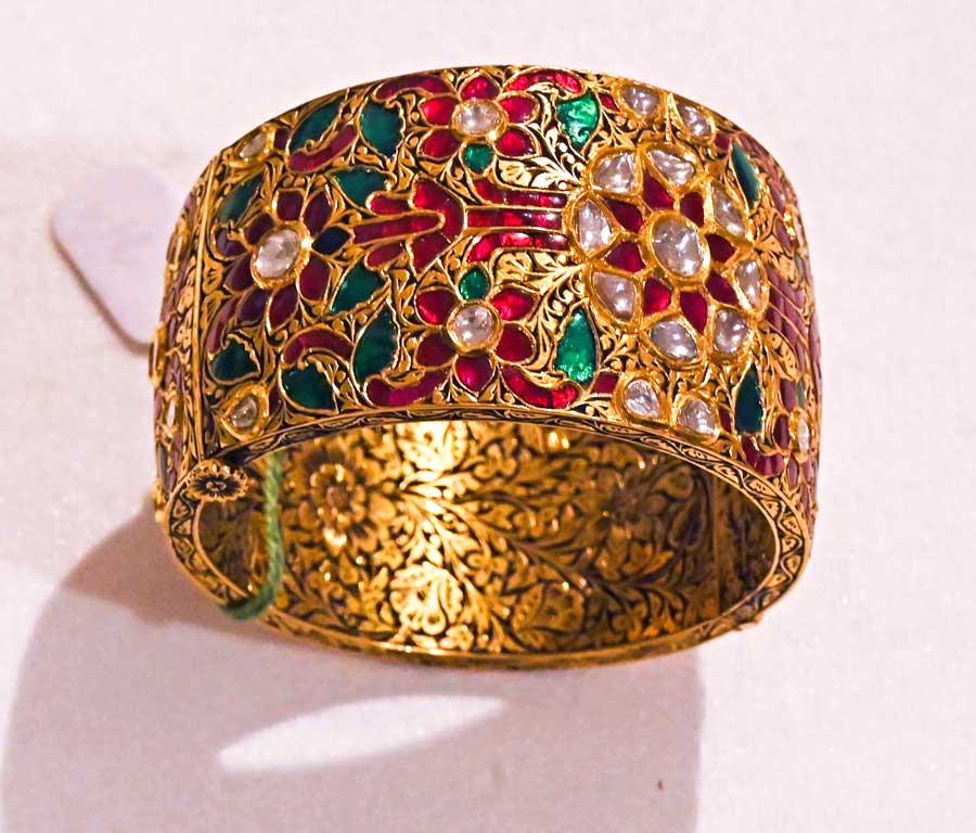 A gold wrist piece designed by Kundan Lal Verma, encrusted with rubies, emeralds, uncut diamonds and delicate engraving work