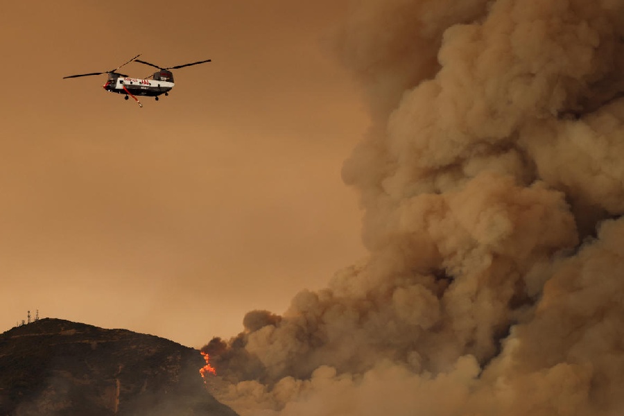 A helicopter flies, as the Airport Fire burns in the hills of Orange County, California, U.S.