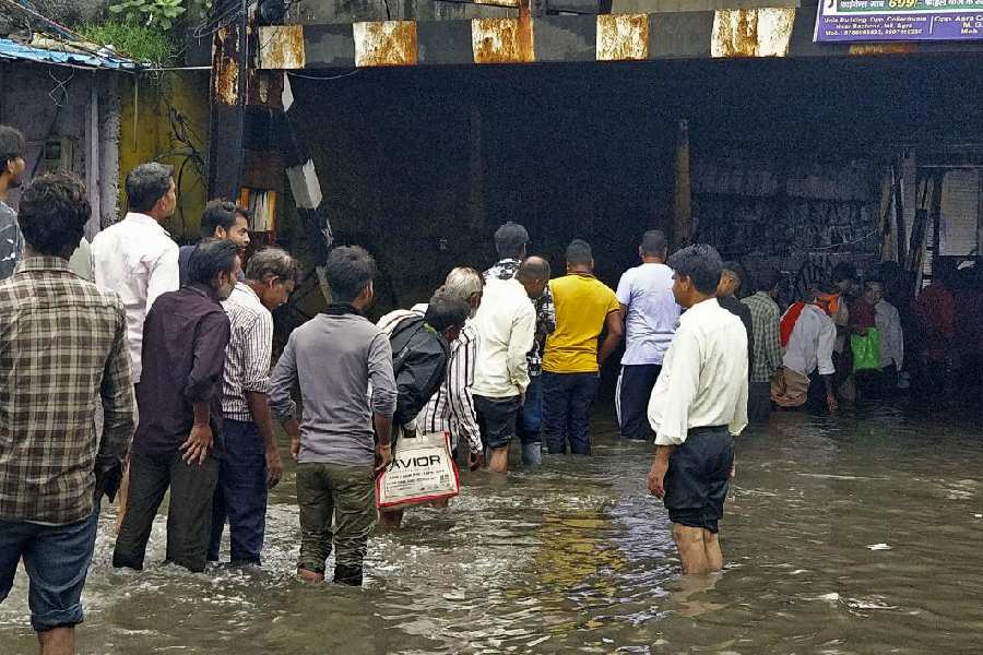 Commuters wade through a waterlogged road during rains.