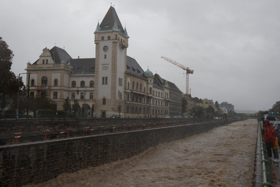 A person holding a smartphone stands next to the flooded Wienfluss river channel during heavy rain, after Austrian forecasters expanded a warning for extreme rainfall to areas of the country including the capital, in Vienna, Austria.