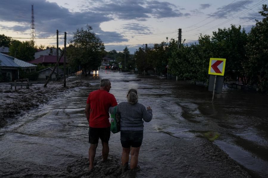 A couple walks on a flooded road after heavy rain triggered flooding in Slobozia Conachi, Galati county, Romania.