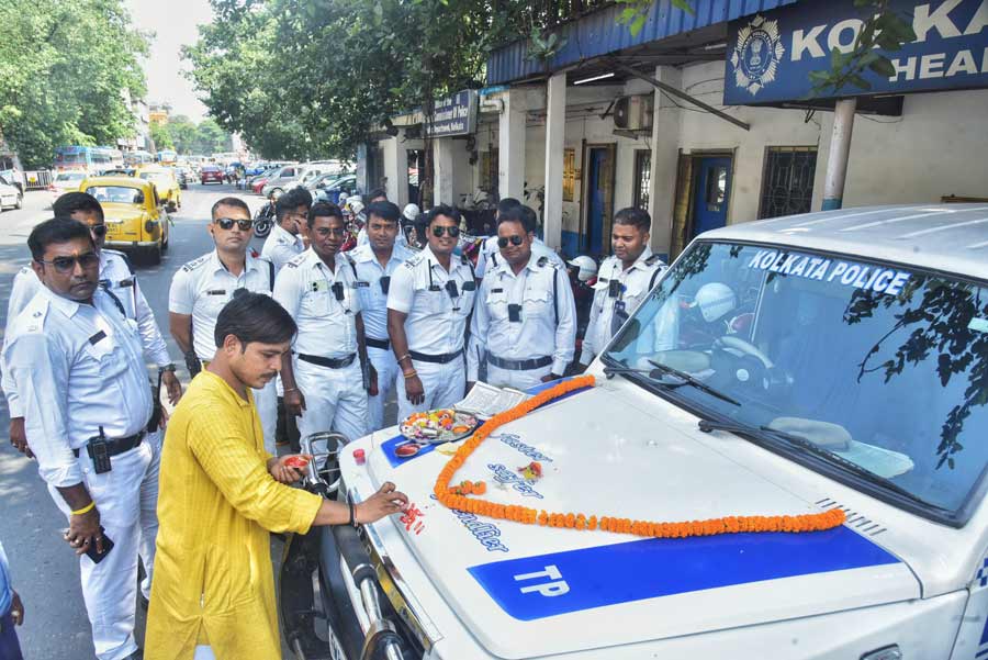 A priest performs puja rituals on police cars at the Kolkata Traffic Police guard post in Esplanade on Vishwakarma Puja 