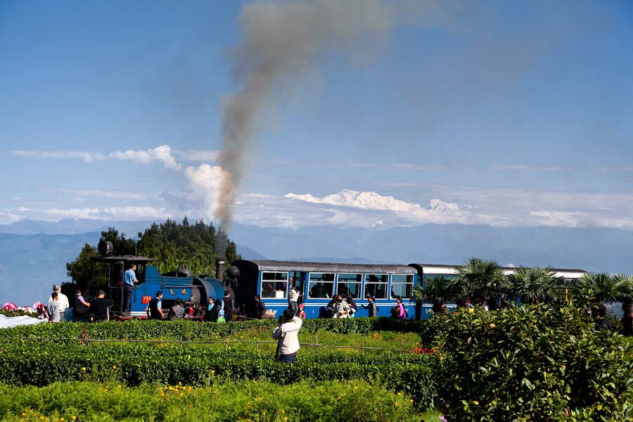 A Darjeeling Himalayan Railway ‘toy train’ chugs along, with Himalayan peaks in the background