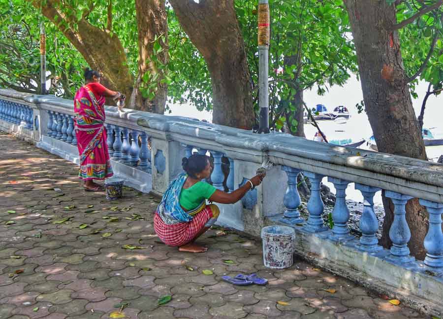 Workers paint railings on the Kolkata riverfront ahead of Durga Puja  