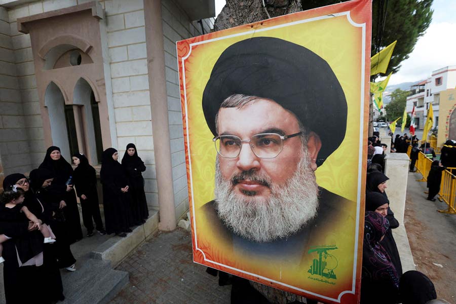 People stand near a picture of Hezbollah leader Nasrallah during the funeral of Hezbollah member Ali Mohamed Chalbi, after hand-held radios and pagers used by Hezbollah detonated across Lebanon, in Kfar Melki, Lebanon on September 19, 2024. 