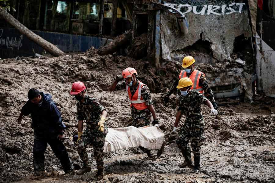 Rescue personnel work to retrieve the bodies of victims from a landslide triggered by heavy rainfall, in Dhading