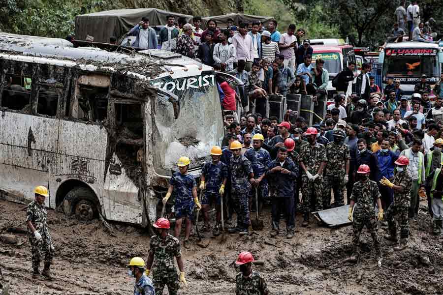 Rescue personnel work to retrieve the bodies of the victims from a landslide triggered by heavy rainfall in Dhading.