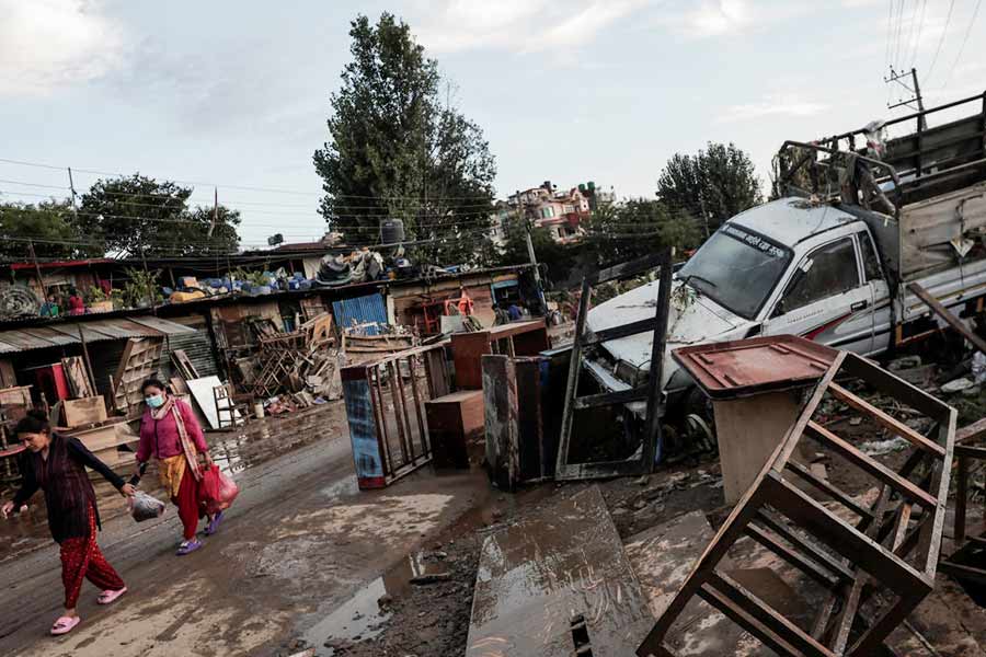 People walk past the debris along the street as the floodwater recedes in an area that was flooded by the overflowing Bagmati River following heavy rains, in Kathmandu.