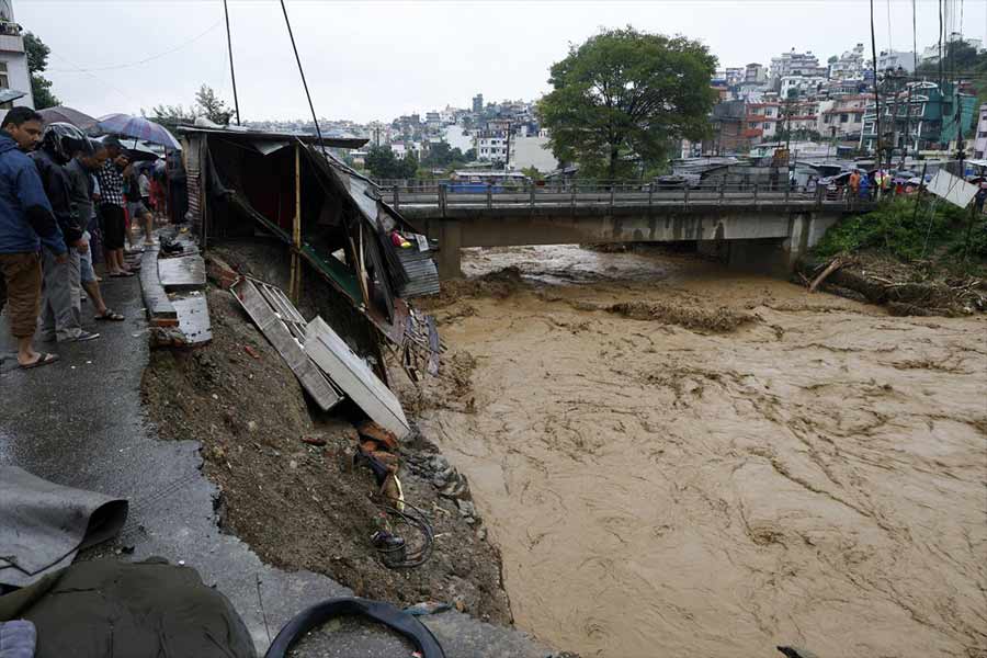 People gather at the edge of the Bagmati River in spate after heavy rains in Kathmandu.