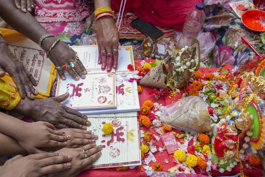 People offer prayers as a trader's account book is seen marked with holy symbols on 'Poila Boisakh' or Bengali New Year's day, in Kolkata, Tuesday, April 15, 2025. Traders in West Bengal open their new account books for the year on Bengali New Year after offering prayers to Goddess Lakshmi and Lord Ganesh.