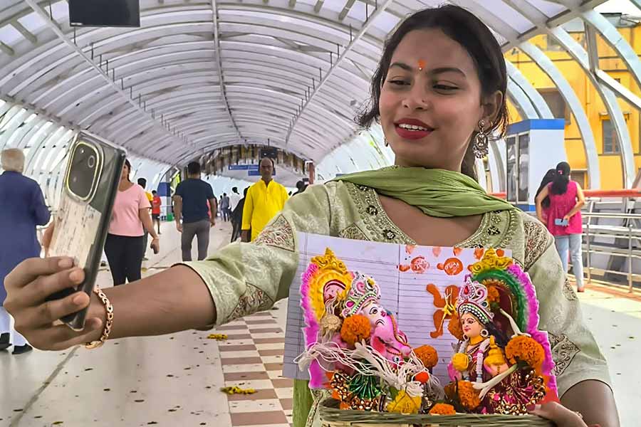 A young woman takes selfies with the idols of Ganesh and Lakshmi on the Kalighat Skywalk  