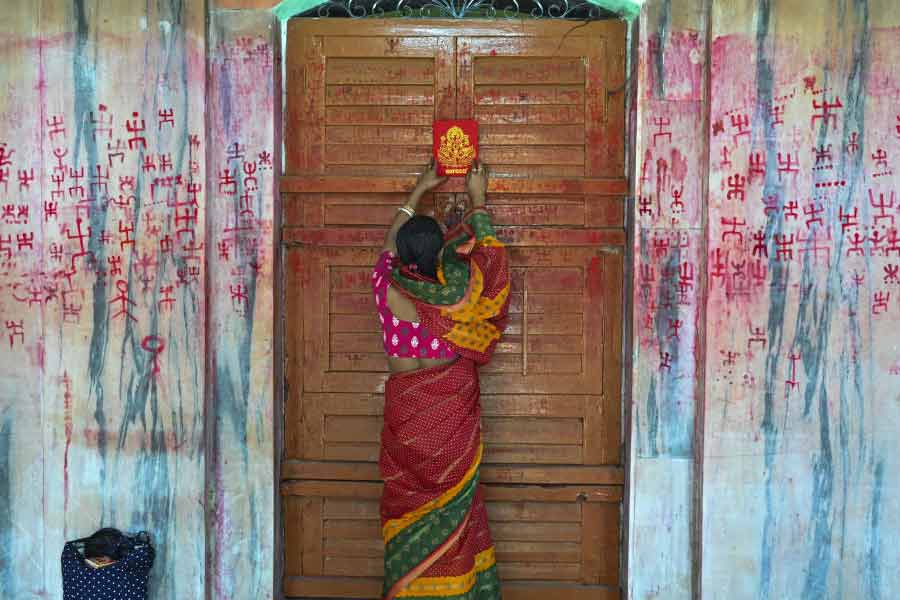 A woman hangs a picture of Lord Ganesh on the door of her house, on Bengali New Year's day, in Agartala.