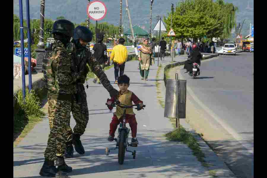 Security personnel manning the banks of the Dal Lake speak to a child riding a bicycle on Sunday.