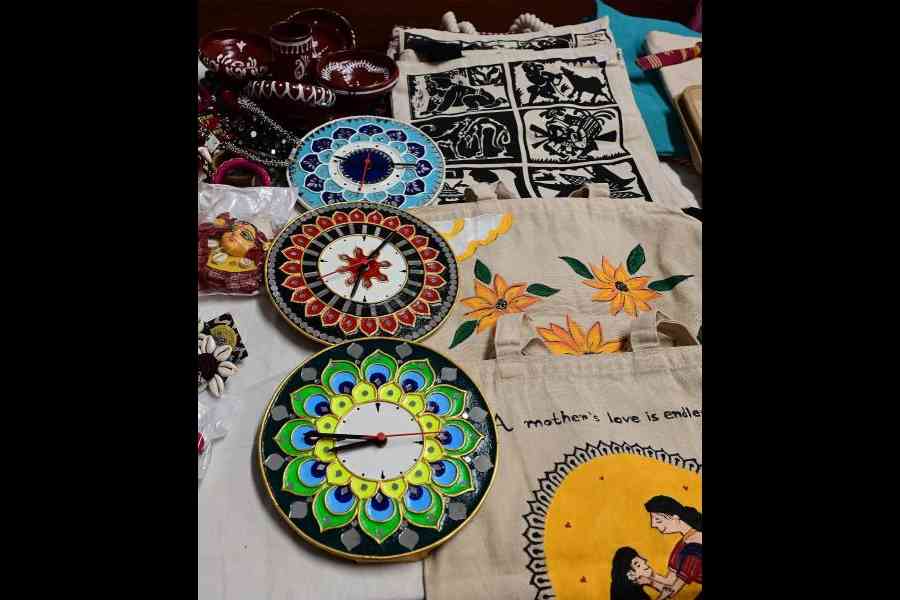 Clay clocks and tote bags with prints of Sahaj Path linocut paintings at the Kolkata Society of Cultural Heritage counter