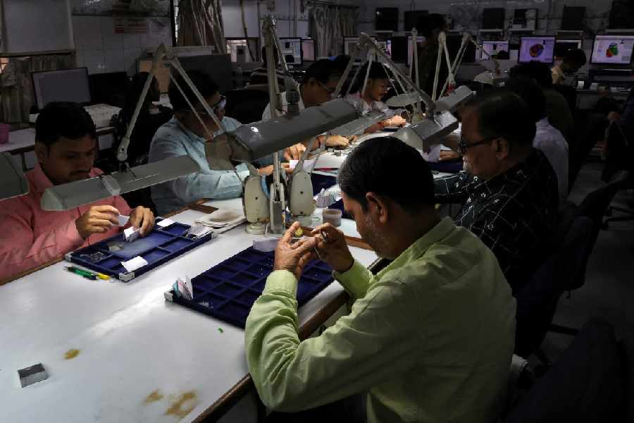 Workers check the grading of polished diamonds at a diamond processing unit in Ahmedabad