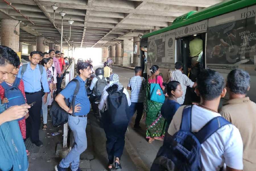 Commuters rush to a bus that stops outside the Sector V Metro station