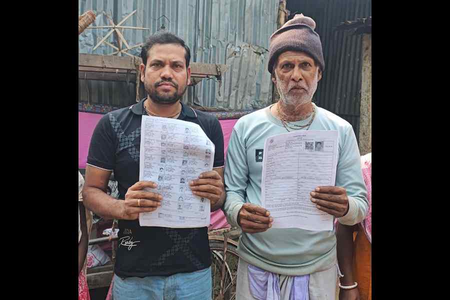 Subhash Chandra Roy (right) holds up the enumeration form issued for his non-existent ‘son’, as his real son Govinda shows the voter list.
