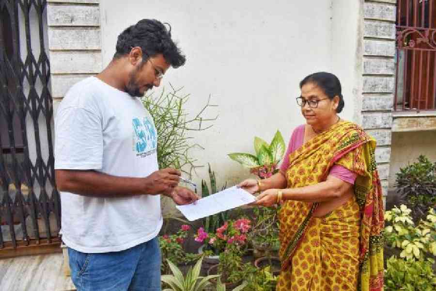 A BLO hands an enumeration form to a woman in Nabadwip. File picture