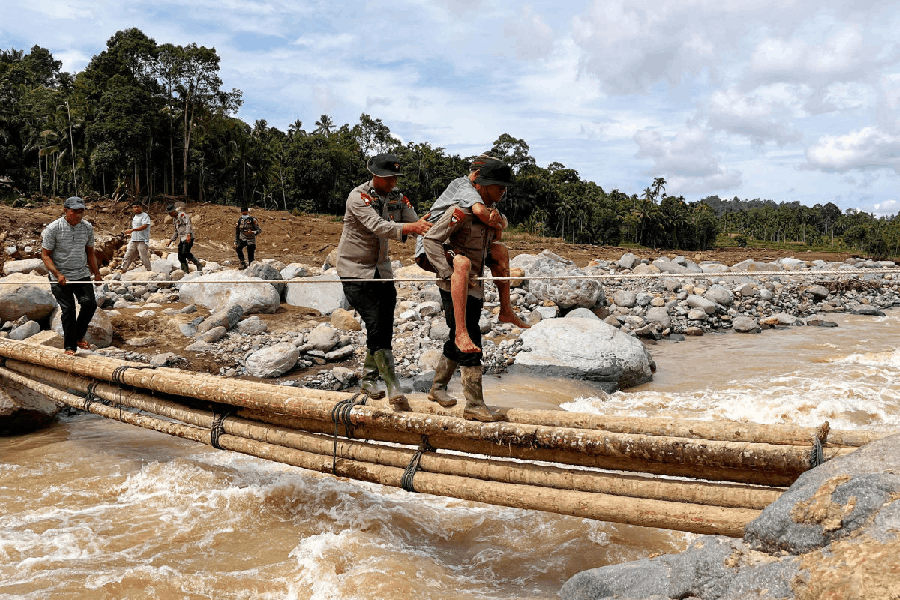 Police officers carry a resident across a wooden bridge in an area hit by deadly landslides following heavy rains, in Palembayan, Agam Regency, West Sumatra Province, Indonesia.