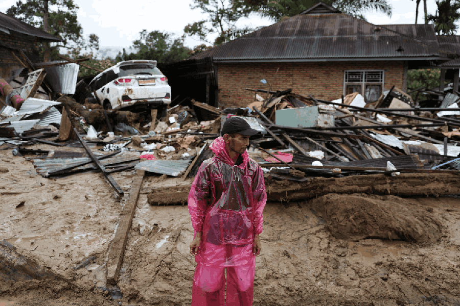 A soldier, along with local residents, carries relief supplies to be distributed to people at an area hit by deadly flash floods following heavy rains in Palembayan, Agam regency, West Sumatra province, Indonesia, December 2, 2025.