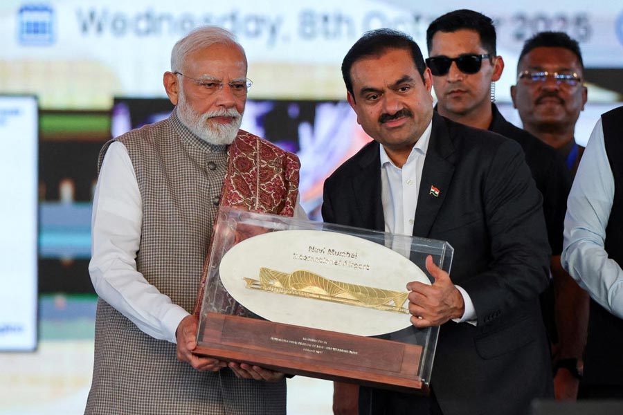 FILE PHOTO: Indian businessman Gautam Adani presents a plaque to India's Prime Minister Narendra Modi during the inauguration event of the Navi Mumbai International Airport in Ulwe, Raigad district, India, October 8, 2025.