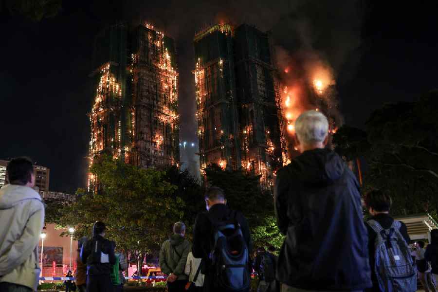 People watch the flames and thick smoke rising from multiple residential blocks at the Wang Fuk Court housing complex during a deadly fire, in Tai Po, Hong Kong, China, November 26, 2025.