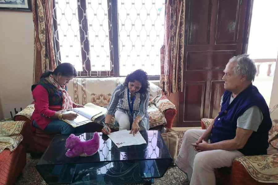Moumita Saha (centre), the booth-level officer for Part 133, fills up a form in a voter's home in AE Block