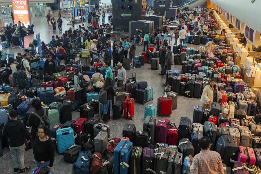 Stranded passengers search for their luggage near a counter after IndiGo cancelled more than 400 flights, at the Kempegowda International Airport, in Bengaluru, Karnataka, Friday, Dec. 5, 2025.