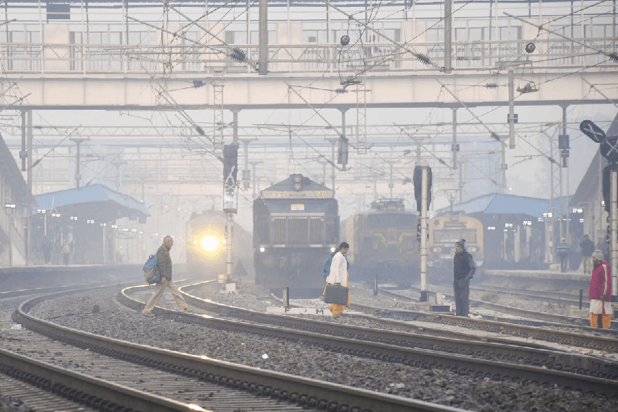 People cross railway tracks amid fog on a winter morning, in Prayagraj.