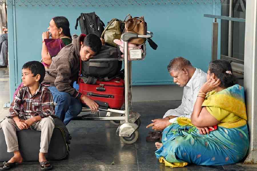 A family waits outside the airport after their flight to Chennai was delayed on Friday. Pictures by Bishwarup Dutta