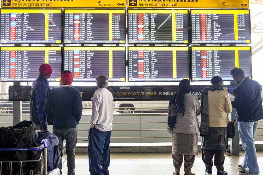 Passengers look at a big display showing check-in information at Terminal 3 (T3) of the Indira Gandhi International Airport, in New Delhi, Saturday, Dec. 6, 2025.