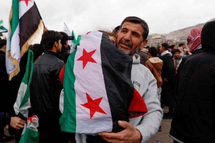 A man carries a girl wearing the Syrian flag at Ummayad Square in Damascus on Monday.
