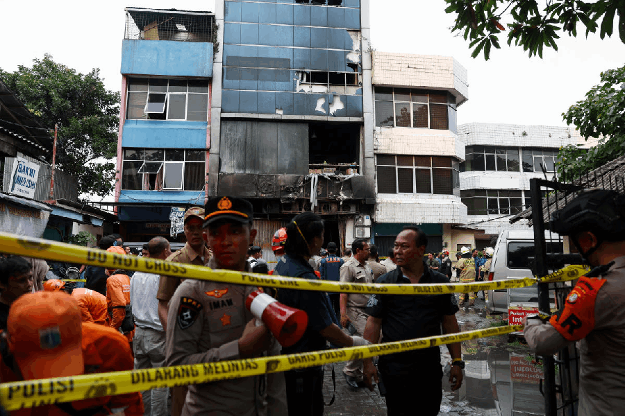 Police officers stand near a seven-storey building damaged by fire, in Jakarta, Indonesia, December 9, 2025.